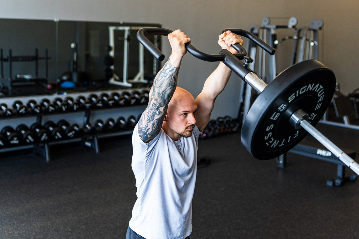 Lifter pressing the Viking Press overhead in an industrial gym