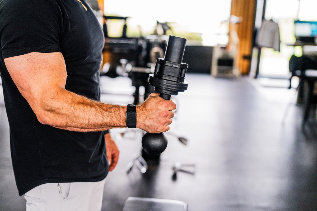 Athlete picking up I-Bell from gym floor, showing compact size